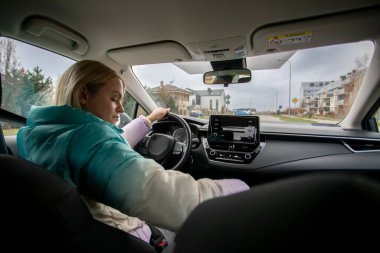 Bir kadın, modern iç tasarımı olan şık bir arabayla şehri dolaşırken yoğun bir şekilde sürüşüne odaklanır.