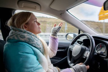 Rahat giyimli rahat bir kadın, serin bir günde duygularını ifade ederken arabasını kullanır.