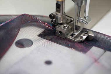 Renkli iplikleri sanatsal olarak kullanırken hassas kumaş üzerinde ustalıkla çalışan bir dikiş makinesinin ayrıntılı görünümü