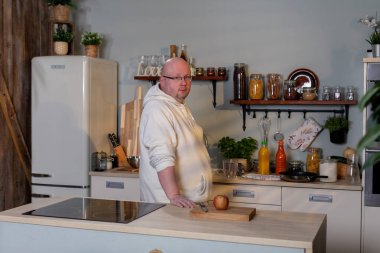 Konforlu, misafirperver bir mutfakta, yetenekli bir şef, sağlam ahşap bir tezgahta taze, canlı sebzeler hazırlar.