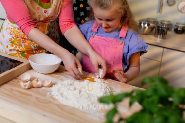 Sevgi dolu bir ebeveynin ve çocuklarının birlikte mutfakta hamuru hazırlarken mutlu ve keyifli bir sahnesi.