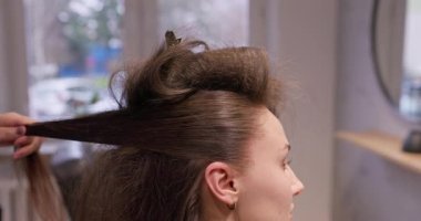 Bir kadın, şık ve modern bir salon ortamında, yetenekli bir profesyonel tarafından saçını güzel bir şekilde şekillendiriyor.