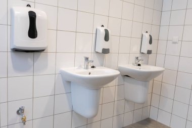 Burası temiz ve modern bir banyo. Halkın rahatı için çift lavabo ve el kurutma makineleri sergileniyor.