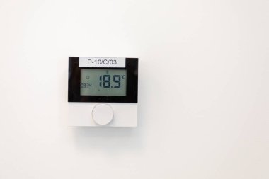 Gösterişli bir termostat düz beyaz bir duvarda 18.9C derece sıcaklık gösteriyor.