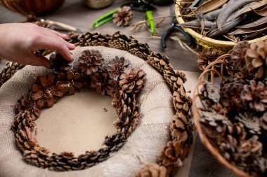Konforlu ve güzel bir kozalak çelengi el işi. Güzel mevsimlik dekorasyon için doğal elementler kullanılıyor.