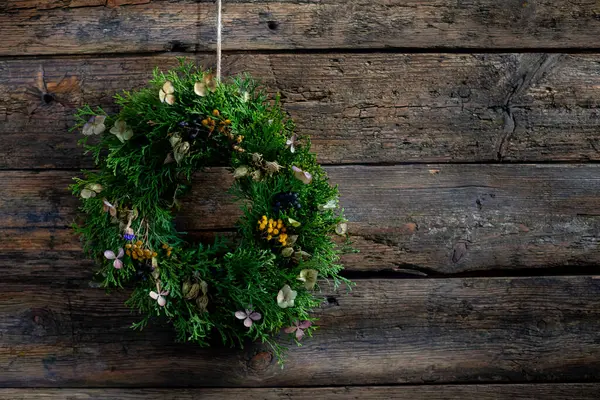 Çok güzel yeşil bir çelenk çeşitli çiçeklerle süslenmiş yıpranmış ahşap bir zemine kurulmuş.