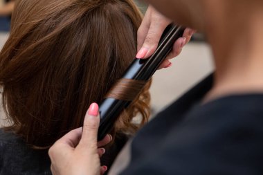 Bir stilist, ileri düzey bir demir tekniği kullanarak müşterinin saçını ustalıkla kıvırmaktır.