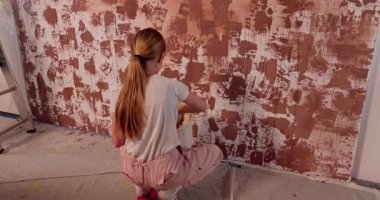 Bir kız desenli bir duvar boyuyor, ev dekorasyonundaki yaratıcılığını sergiliyor ve dokunuşuyla mekanı değiştiriyor.