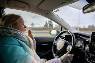 Sıcak bir eşarba sarılmış yorgun bir sürücü serin bir öğleden sonra yollarda gezinirken geniş bir yelpazede esniyor.