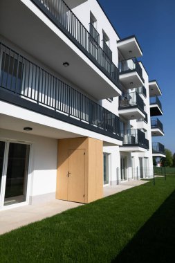 Modern bir dairede zarif balkonlar, parlak güneş ışığında yemyeşil çimenler, göz alıcı bir mimari sergileniyor.