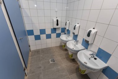 Çok sayıda pisuvarın bulunduğu temiz ve çağdaş bir tuvalet ve hijyen için el dezenfektanı.