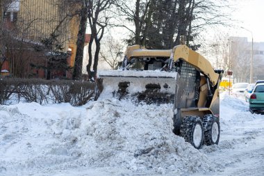 Güçlü bir kar küreme aracı kış mevsiminde karla kaplı bir sokağı özenle temizliyor.