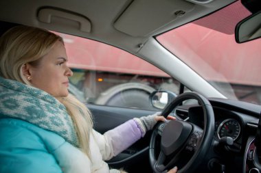 Şehirde arabasını ustalıkla kullanan bir kadın, odaklanma ve modern seyahat deneyimini gösteriyor.