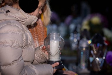 Bir kadın nazikçe titreyen bir mumu gece boyunca çeşitli anlamlı anılardan oluşan bir dizinin yakınında tutar.