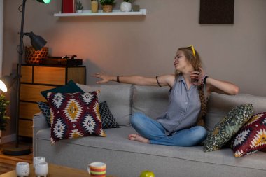 Neşeli, neşeli genç bir kadın uzuvlarını neşeyle uzatıyordu rahat, canlı bir oturma odası atmosferinde bir kanepeye.