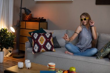 Rahat bir akşam sahnesinde, şık güneş gözlüğü takan bir insan sıcak ve rahat yaşam alanının tadını çıkarıyor.