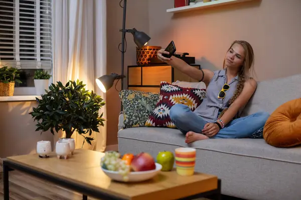 Bir kadın lezzetli çerezler ve canlı bitkilerle dolu sıcak bir oturma odasında sıcak bir akşamın tadını çıkarır.