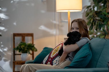 Yürek ısıtan ve davetkar bir an, hoş bir köpeği nazikçe tutan genç bir kızı oturma odasında yakalar.