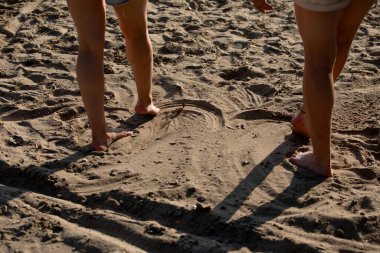 Çıplak ayaklı, kumlu bir sahilde duran, sakin bir dinlenme anını yakalayan ve yazın güneşin altında eğlenen