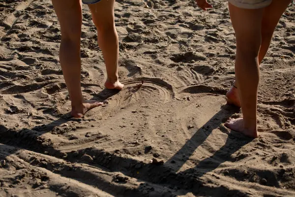 Çıplak ayaklı, kumlu bir sahilde duran, sakin bir dinlenme anını yakalayan ve yazın güneşin altında eğlenen