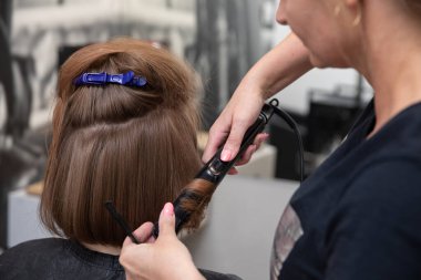 Modern bir kuaförde kuaförlük tekniklerini ve sanatını sergileyen profesyonel bir stilist.