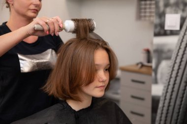 Genç bir müşteri şık, modern bir kuaförde şık ve lüks bir saç kesiminin keyfini çıkarıyor.