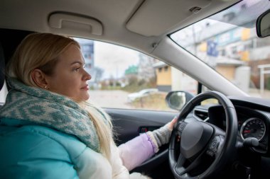 Serin bir günde arabasını süren bir kadın, sakin bir konsantrasyon sergilerken şık kış modasını sergiliyor.