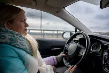 Bir kadın kış manzarasında, ceketi ve atkısıyla sıcacık bir şekilde yolculuk ederken, yolculuğunu düşünüyor.