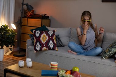 Genç bir kadın evinde rahat bir akşamın tadını çıkarıyor. Etrafı abur cubur ve dekorla çevrili. Bu onun yaşam alanını genişletiyor.