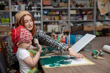 Bir çocuk ve bir yetişkin parlak ve yaratıcı bir mekanda renkli bir sanat seansının keyfini çıkarıyorlar.