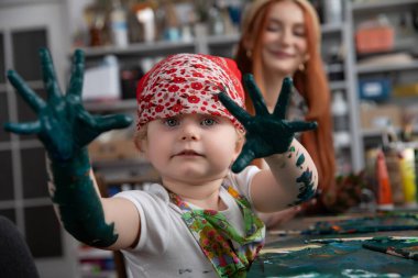 Genç bir sanatçı renkli bir resim seansından zevk alır. Yaratıcılığı dağınık, boyalı ellerle ifade eder.