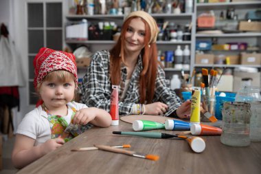 Bir çocuk ve yetişkinin resim faaliyetleri yoluyla yaratıcılığı ve renkleri keşfettiği neşeli bir sanat oturumu gerçekleşir.