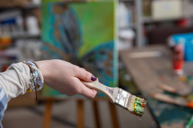 Zarif bir el, ilham verici bir sanat stüdyosunda canlı ve renkli bir fırça tutar.