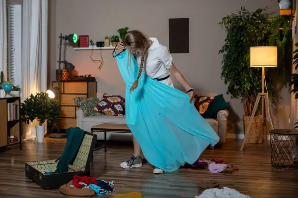 Bir kadın şatafatlı evinde parlak ve renkli kıyafetlerle dolu şık bir bavul hazırlıyor.