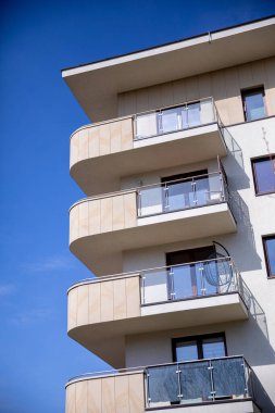 Modern çağdaş bir apartman dairesi zarif balkonlarını canlı mavi gökyüzüne karşı güzelce sergiliyor.