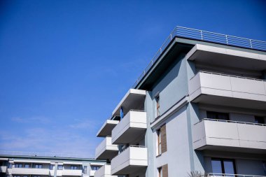 Çağdaş bir apartman kompleksi, canlı, berrak mavi gökyüzüne karşı modern mimariyi güzel bir şekilde sergiliyor.