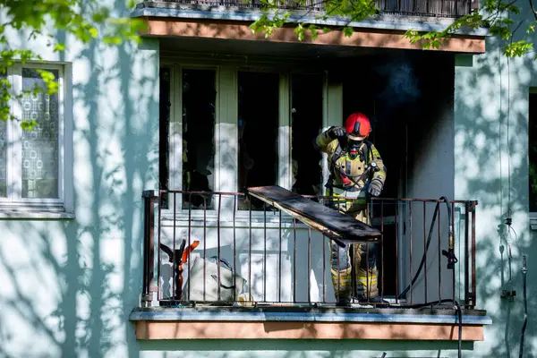 İtfaiyeci, bir apartmanın balkonunda alevlerle cesurca savaşıyor. Güvenliği ve etkili kurtarmaları sağlıyor.