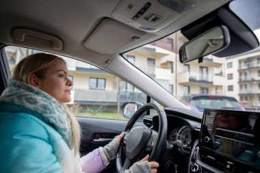 Şık bir araba süren bir kadın, kentin hareketli ortamında rahatça dolaşır.