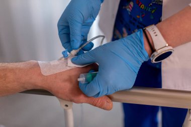 Klinik bir ortamda, yetenekli bir hemşire ihtiyacı olan bir hastaya damardan tedavi uygular.
