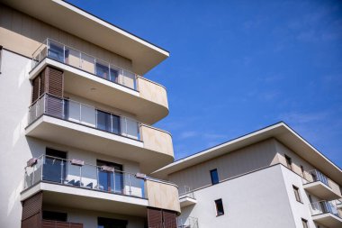 Modern mimari ve balkonları parlak gökyüzünün altında barındıran çok katlı bir apartman kompleksi..