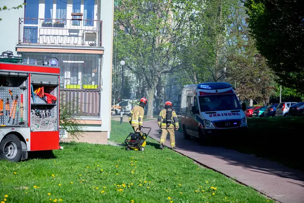 İtfaiyeciler ve ambulans dumanla dolu bir yerleşim yerine gelerek acil müdahale çabalarını vurguluyor..