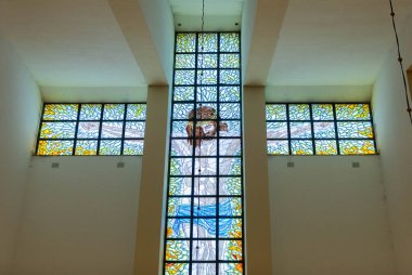 Çağdaş bir kilise ortamında haç sergilenen karmaşık bir vitray tasarımı.