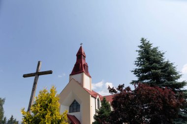 Sakin ve güzel bir kilise, canlı ağaçlar ve bereketli doğayla çevrili parlak mavi bir gökyüzüne karşı dimdik ayakta duruyor.