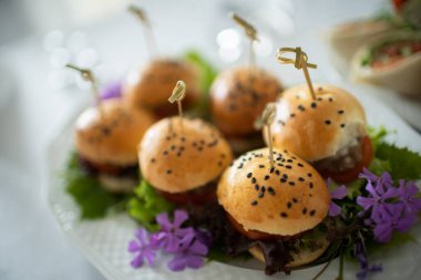 Lezzetli bir tabak mini burger. Taze otlar ve yenilebilir çiçeklerle süslenmiş. Her şey için mükemmel.