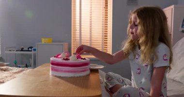 Genç bir kız, keyifle renkli bir doğum günü pastasının tadını çıkarırken, bugün sıcak bir hastane odasında oturuyor.