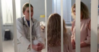 Genç bir kız ve annesiyle tıbbi bir ortamda etkileşime giren bir doktor şefkat gösteriyor..
