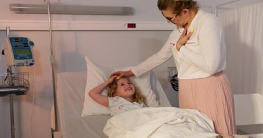Şefkatli bir bakıcı, hastane yatağında yatan genç bir kıza duygusal destek veriyor.