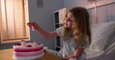 Genç bir kız hastanede renkli bir doğum günü pastasından zevk alır. Her ısırıkta hem neşe hem de üzüntü hisseder.