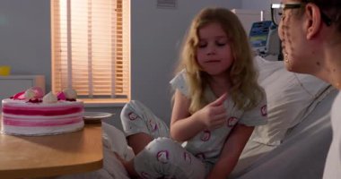 Bir kız, hastanede zor zamanlarda bile mutluluk saçan lezzetli bir pastadan zevk alır.