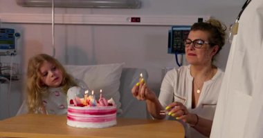 Sadık bakıcılarıyla birlikte bir çocuk hastane ortamında samimi ve neşeli bir doğum gününü kutluyor.
